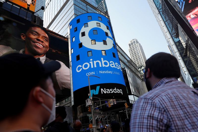 FILE PHOTO: People watch as the logo for Coinbase Global Inc, the biggest U.S. cryptocurrency exchange, is displayed on the Nasdaq MarketSite jumbotron at Times Square in New York